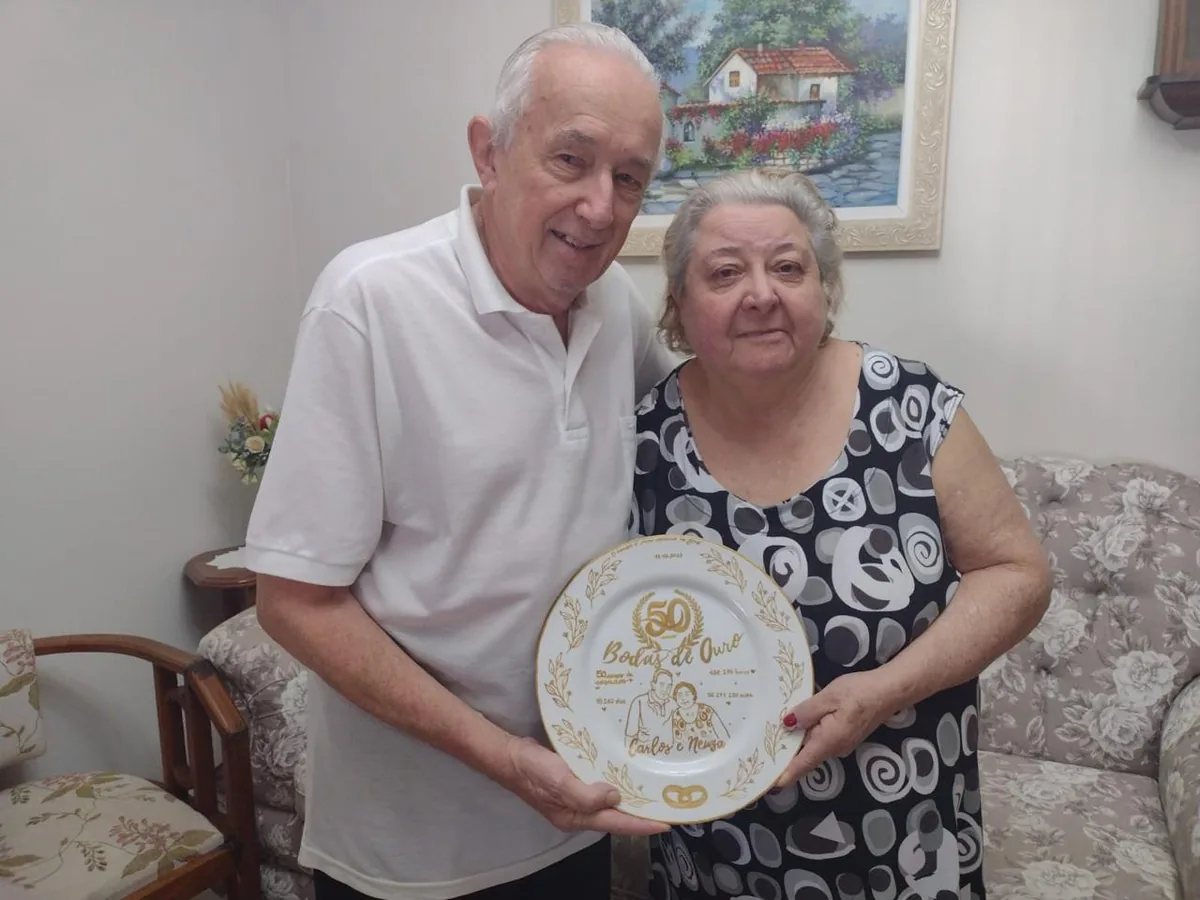 Casal segurando prato personalizado de Bodas de Ouro